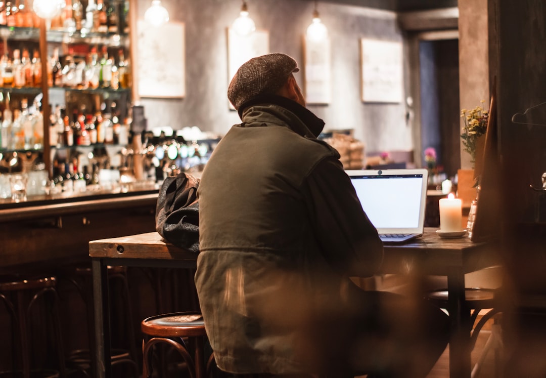 夜のバーカウンターに一人座る中年男性の後ろ姿-ヘッダー画像-