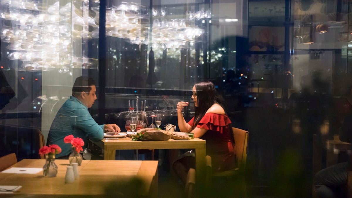 レストランのガラス越しに向かい合う男女-ヘッダー画像-